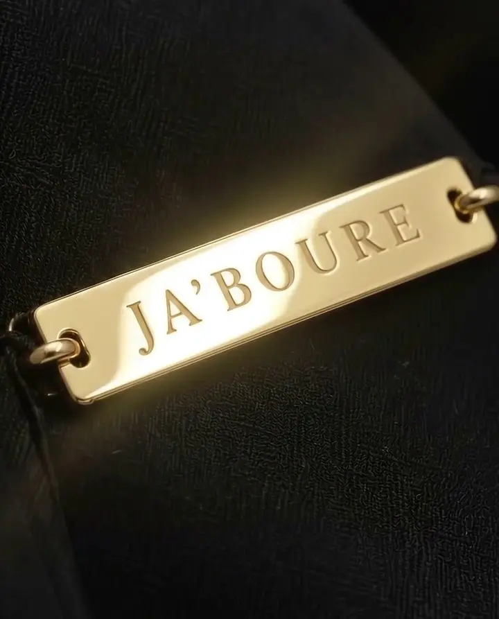 The gold JA'BOURE plate on black fabric